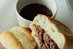 close up view of a sandwich and Easy Slow Cooker French Dip in a bowl in the background
