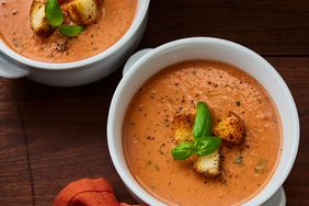 looking at two bowls of rich and creamy tomato basil soup garnished with croutons and fresh basil 