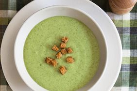 Bowl of the best cream of broccoli soup topped with croutons sitting on a plaid linen.