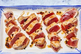 several medium rare seared tuna steaks are sliced on a blue and white platter.