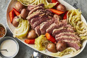 overhead view of corned beef sliced and on a platter with cabbage, potatoes, and carrots