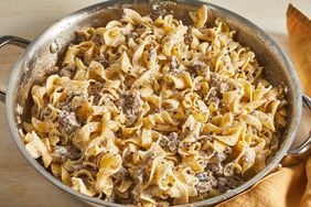 close up view of beef stroganoff in a pan, next to a kitchen towel