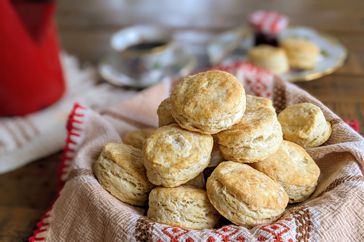 a heaping pile of fresh golden-brown basic biscuits in a towel lined basket 