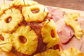 looking at a brown sugar and pineapple glazed ham resting on a cutting board with a few slices cut