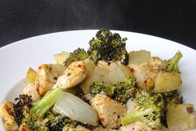 close up view of Baked Italian Chicken Dinner with broccoli, potatoes, and onions in a white bowl