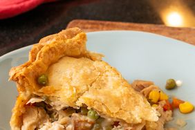 a low angle view of a single slice of leftover turkey pot pie with golden-brown crust on a light blue plate.