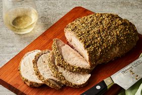 a high angle view of a roasted pork loin on a cutting board partially sliced
