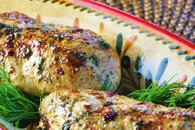 close up view of baked chicken breasts on a colorful platter with herbs