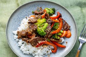 a close up, overhead view of a single serving of beef stir fry served over white rice