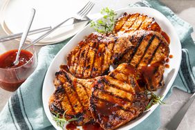 Family style platter of World's Best Honey Garlic Pork Chops garnished with extra sauce and fresh herbs.