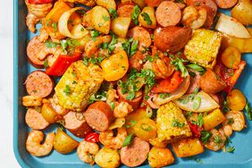 an overhead view of sheet pan shrimp and sausage bake on a bright blue sheet pan. 