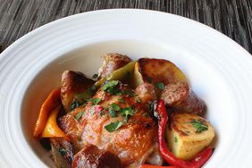 close up view of Chicken, Sausage, Peppers, and Potatoes garnished with fresh herbs in a white bowl