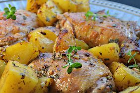 A platter of chicken thighs and roasted potatoes, garnished with fresh thyme