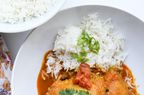 top-down view of chicken curry in a white bowl with Basmati rice, garnished with cilantro