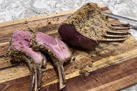 Roasted rack of lamb with 3 perfectly pink ribs cut off on a wooden board