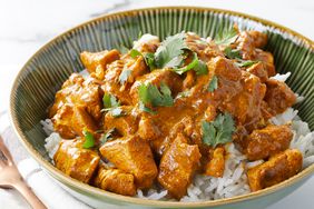 high angle looking at a bowl of Indian Chicken Curry garnished with fresh herbs served on top of rice