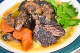close up view of Braised Beef Cheeks werved with fresh herbs and carrots on a plate