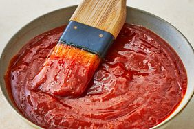 a close up view of barbecue sauce with a brush sitting in the sauce.