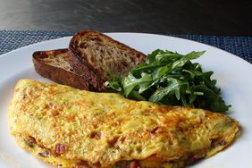 close up view of a Denver omelet with toast and an arugula salad on a plate