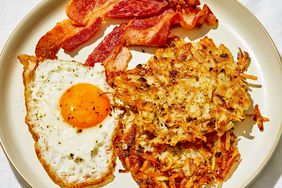 close up view of Homemade Crispy Hash Browns served with a fried egg and bacon on a plate 