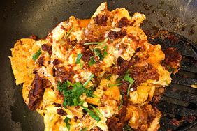 close up view of Scrambled Eggs with Chorizo garnished with fresh herbs in a pan