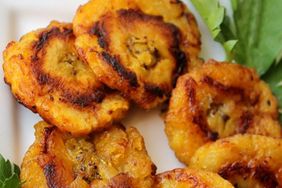 close up view of Puerto Rican Tostones (Fried Plantains) with herbs on a platter