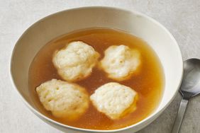 a close up view of a bowl with four fluffy dumplings in a clear broth