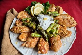 chicken with asparagus and lemon caper cream on a red table cloth with beige napkin