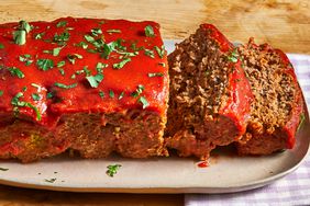 close up view of sliced Meatloaf garnished with fresh herbs on a platter 