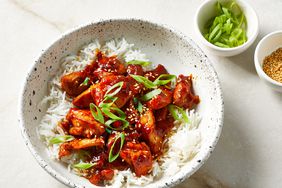 Close up on a bowl of white rice, topped with sweet and spicy gochujang chicken.