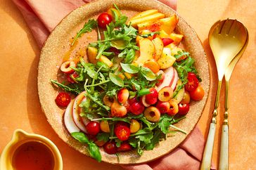 an overhead view of an arugula salad with stone fruits.