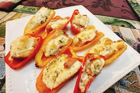 colorful pepper halves filled with cheese and prosciutto on white square plate