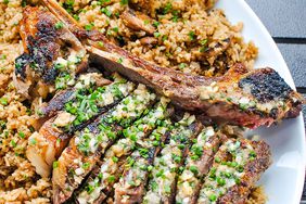 beautifully seared and sliced tomahawk steak topped with bright herb butter on a bed of rice 