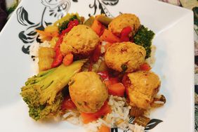 chicken meatballs with stir-fry vegetables over rice on a white plate