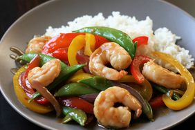 pearl gray bowl of shrimp, snow pea, and red and yellow bell pepper stir-fry on rice