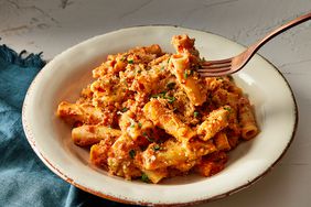 a bowl of baked ziti with a forkful being lifted from the bowl, 