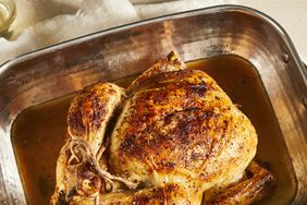 an overhead view of a whole beautiful roasted chicken in a roasting pan.