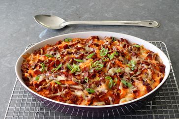 oval casserole dish with bacon and green onion-topped loaded sweet potato casserole