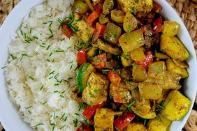 yellow tofu curry with vegetables and rice in white bowl