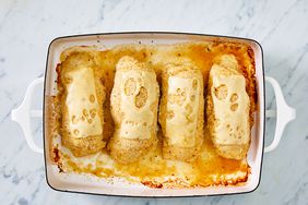 a top down view of 4 golden-brown chicken cordon blues in a baking dish, each topped with melted Swiss cheese