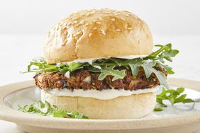 low angle looking at a black bean veggie burger on a bun with arugula, on a beige plate 
