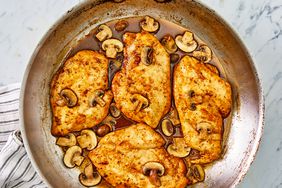 Close up image of chicken marsala with mushrooms and sauce in a metal pan