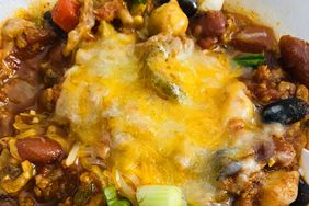 a close up view of vegetarian chili in a bowl, with melted cheese on top