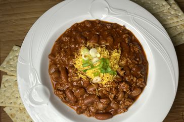 thick bean chili with cheese and green onion garnish
