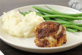 A dinner plate with mashed potatoes, green beans, and crispy chicken