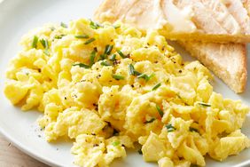 Close up on a plate of creamy cottage cheese scrambled eggs, with a side of toast.