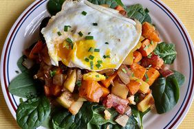 Sweet potato hash over salad with over easy egg on top